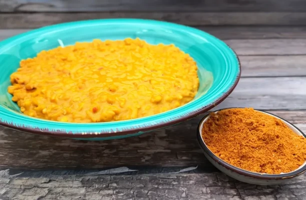 Schüssel mit goldgelbem Linsen-Dal, garniert mit frischem Koriander, daneben Naan-Brot und Reis
