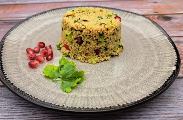 Bunter Couscoussalat mit Granatapfelkernen, Petersilie und Ras el Hanout in einer Schüssel angerichtet