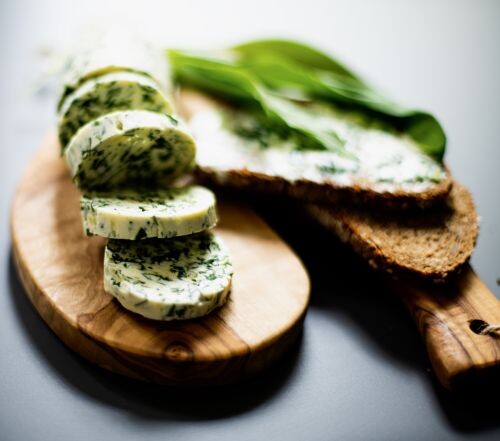 Holzbrettchen mit Scheiben von Brot und Bärlauchbutter