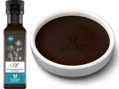 Flasche mit Bio Schwarzkümmelöl der Ölmühle Solling und daneben eine Schale gefüllt mit Öl