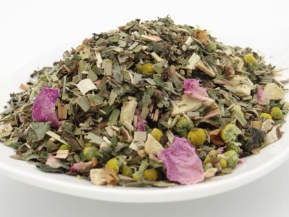 Weiße Schale, gefüllt mit einer getrockneten Kräutermischung aus grünen Blättern, hellen Stängelstücken, gelben Blütenköpfen und vereinzelten violetten Blütenblättern, von der Seite fotografiert.